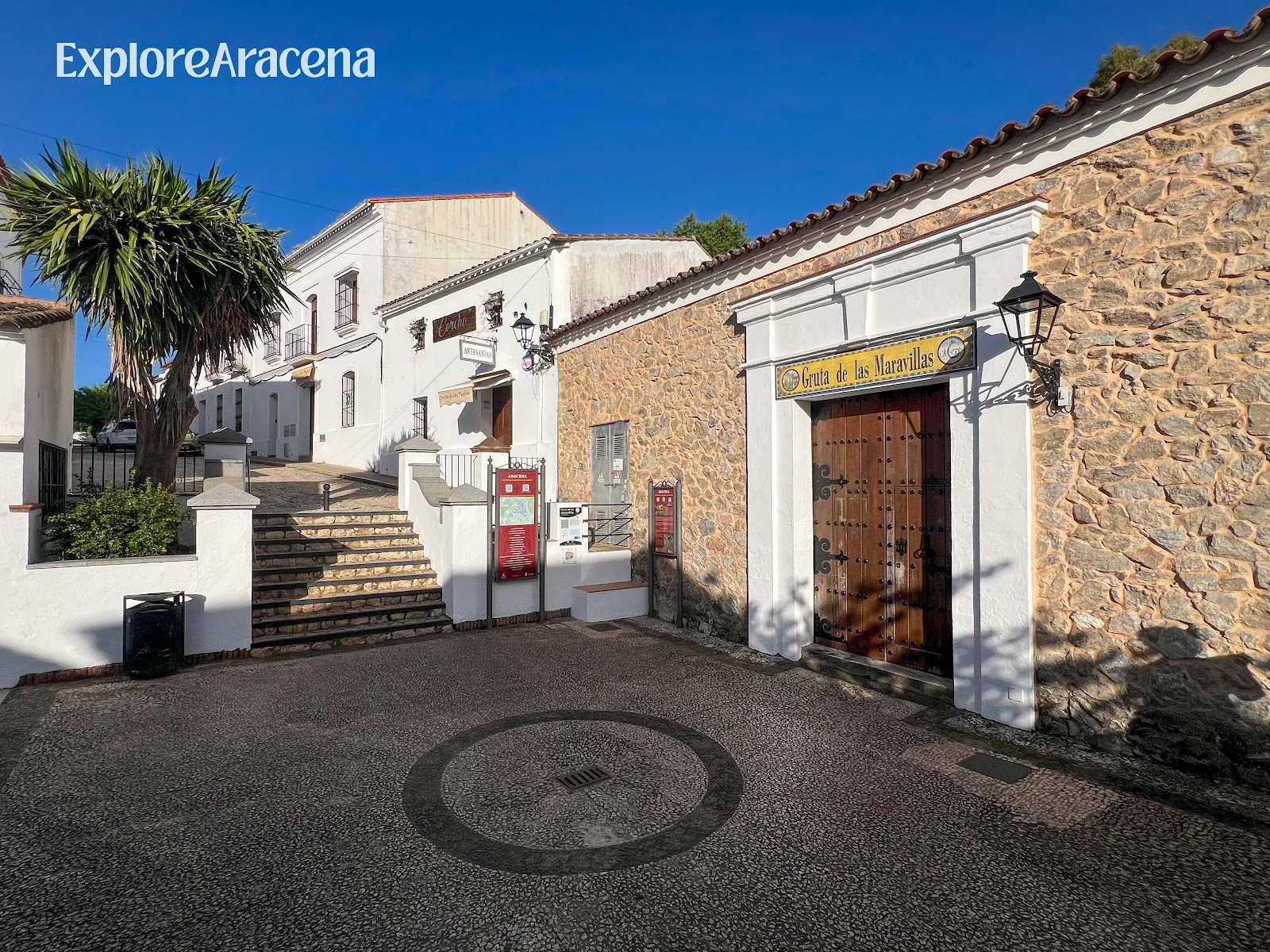 Entrance to the Gruta de las Maravillas, with its doorway and sign visible from the surrounding plaza in Aracena