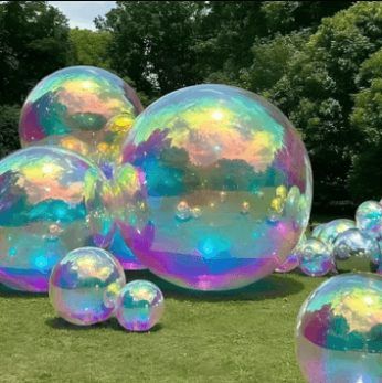 Bulles irisées géantes posées sur une pelouse
