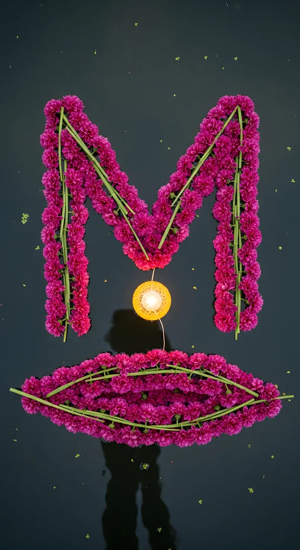 Magenta Flower Letter M and Glowing Diya on Dark Water