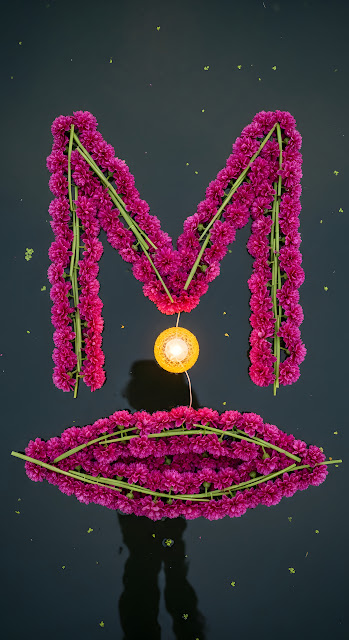 Magenta Flower Letter M and Glowing Diya on Dark Water - Free mobile Wallpaper
