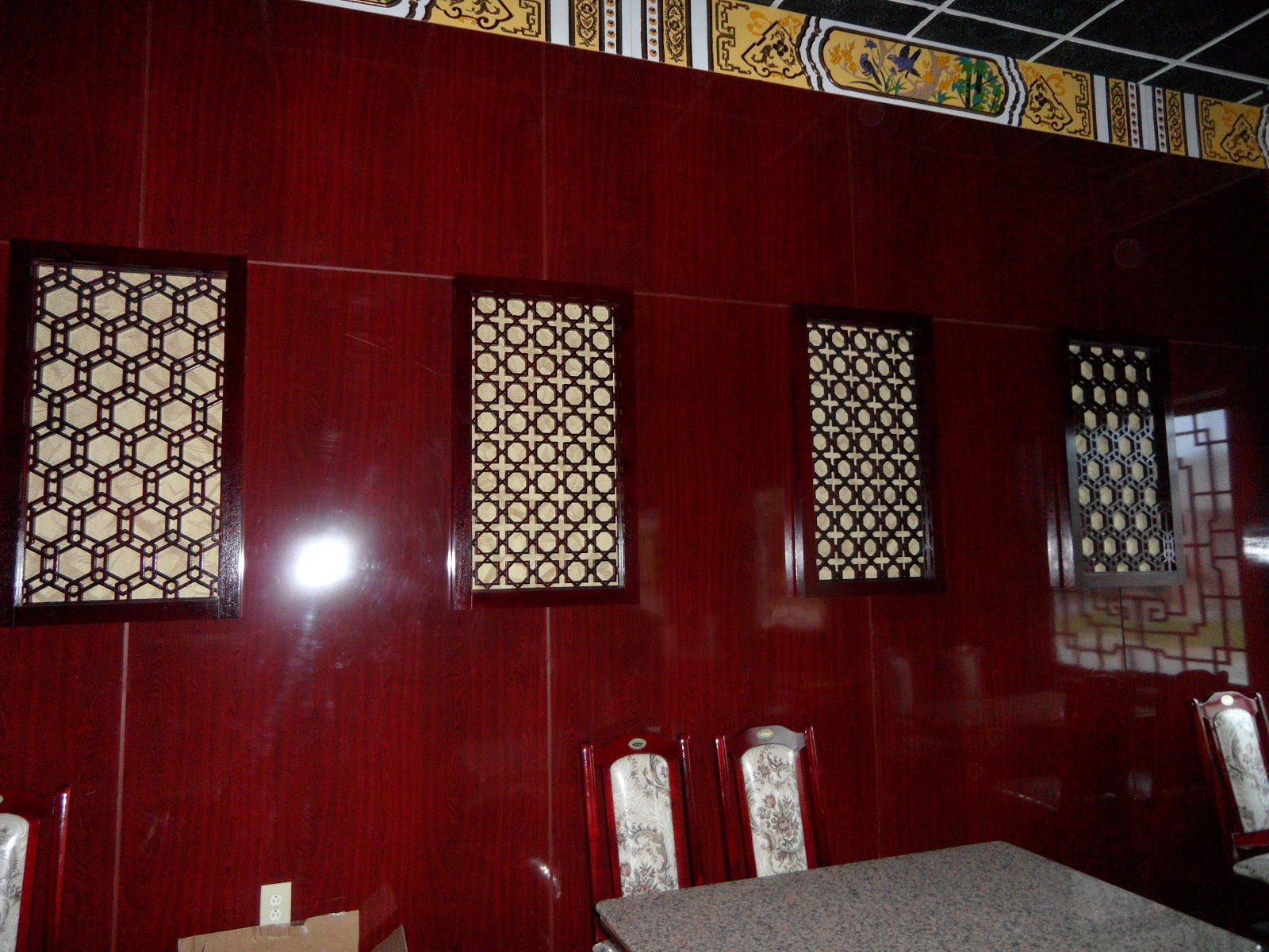 Glossy red wall with four rectangular lattice decorative panels and a patterned border near the ceiling.