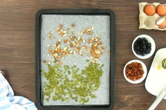 Đầu tiên, chia đều mỗi loại 40gr gồm nho khô đen, nhãn sấy, hạt hạnh nhân và hạt bí xanh. Cắt nhỏ hạt hạnh nhân rồi đem nướng cùng hạt bí xanh ở nhiệt độ 160 - 170 độ C trong khoảng 5 – 7 phút cho hạt thơm giòn.