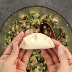 Lấy vỏ bánh dumpling cho từng viên nhân vào phết mỏng lớp nước, rồi nắn thành hình.