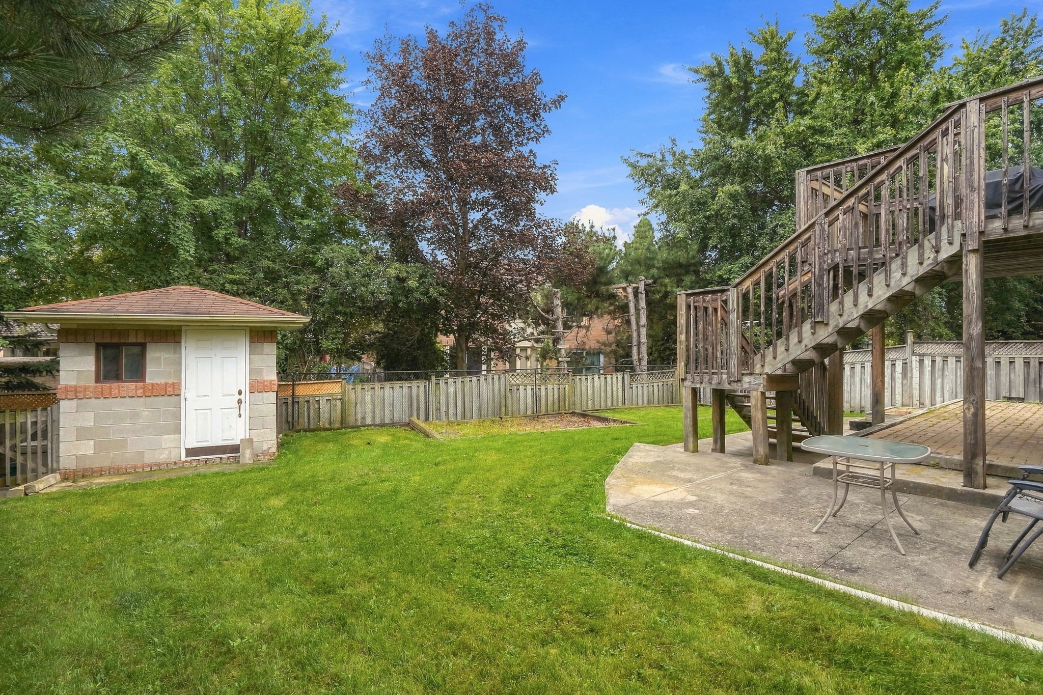 The backyard with the deck, stairs and shed