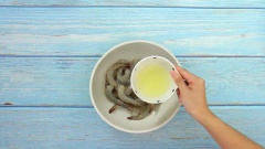 Tôm tươi 500gr các bạn rửa sạch, bỏ vỏ và giữ lại đuôi tôm, để ráo rồi cho vào một cái bát. Ướp tôm với 2 muỗng cà phê bột bắp, 1 cái lòng trắng trứng, 1/4 muỗng cà phê muối và 1/2 muỗng cà phê tiêu xay. Trộn đều tôm rồi ướp trong 20 phút.