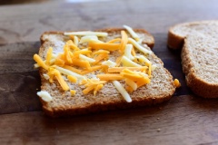 Đặt một miếng bánh mì sandwich lên thớt, phết lớp bơ phỏng, rắc một lớp mỏng phô mai sợi (loại tùy sở thích nhé). Miếng sandwich còn lại cũng phết lớp bơ, rắc thật nhiều phô mai sợi. Lấy miếng sandwich ít phô mai đậy phần không có phô mai lên trên miếng bánh mì còn lại.
