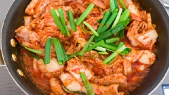 Thêm kim chi đã vắt vào xào cho đến khi kim chi chuyển sang màu hơi nâu. Thêm nước kim chi vào đảo chung, đun sôi trở lại cho đến khi sốt sánh lại thì thêm hẹ và hành lá vào là xong.