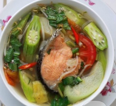 Múc canh chua đầu cá hồi ra tô, rắc rau om ngò gai lên trên mặt và dùng nóng nhé!