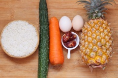 Chẻ đôi quả dứa (quả thơm) theo chiều dọc. Dùng một con dao nhỏ cắt lấy ruột dứa, dùng muỗng múc ruột dứa cho vào tô nước muối loãng, ngâm khoảng 5 phút rồi vớt ra để riêng. Đập 2 quả trứng gà vào chén. Tỏi băm nhỏ. Thái hạt lựu dưa leo, cà rốt, lạp xưởng.