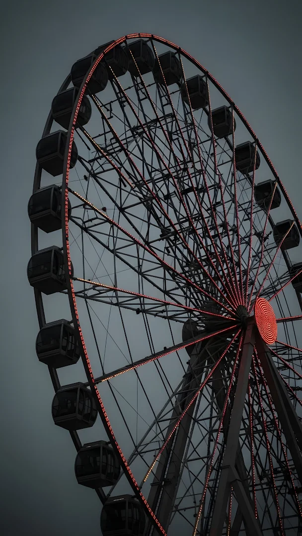 Moody Ferris Wheel with Red Lights Against Dark Sky