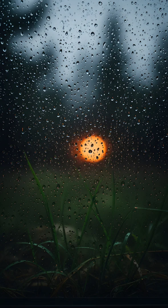 Raindrops on Window Glass with Orange Light Bokeh