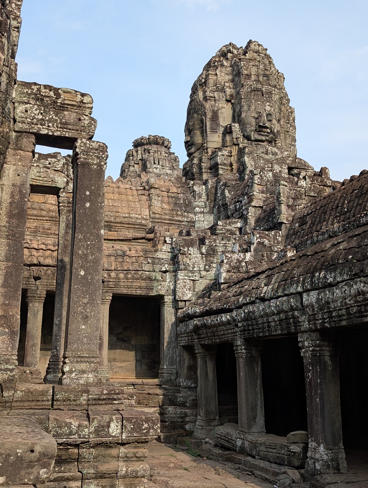 Photo of temple ruins from an internal courtyard with a tower
                 that has large, 3D stone face carved into the blocks of the
                 two visible surfaces of the rectangular tower