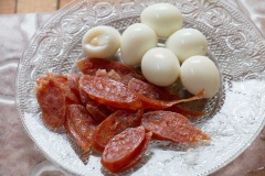 Chuẩn bị làm bánh bao chiên: Luộc sơ lạp xưởng rồi cắt lát mỏng. Luộc chín trứng cút rồi lột vỏ, cho vào chén. Sau khi lột vỏ trứng cút, cho vào tô thì bạn nên rửa sơ lại bằng nước sạch. Do khi lột, trứng bị dính hơi tay, nếu không rửa qua nước thì sẽ dễ thiu.