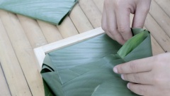 Cắt 1 miếng lá dong xếp lên mặt nếp, sau đó lần lượt xếp các lá lớp lá dong xuống giống như cách gói hộp quà. Khi gói bánh chưng xanh nhớ nén chặt tay để lá dong không bị hở nước luộc sẽ dễ ngấm vào gây nhão bánh. Rút khuôn ra khỏi bánh chưng.