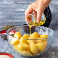 Bật trước lò nướng ở nhiệt độ 400°F/200°C. Lót giấy nến lên khay nến và để riêng sang 1 bên. Khoai tây bạn chà rửa thật sạch, giữ nguyên vỏ, cắt đôi, cho vào tô trộn. Rưới dầu olive và muối vào.
