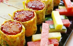 Cuối cùng, đặt chồng viên thịt lên viên cơm rồi quấn trứng ra ngoài và thêm một ít sốt cà chua lên trên cùng. Dùng tăm để gài cho trứng không bị bung ra.