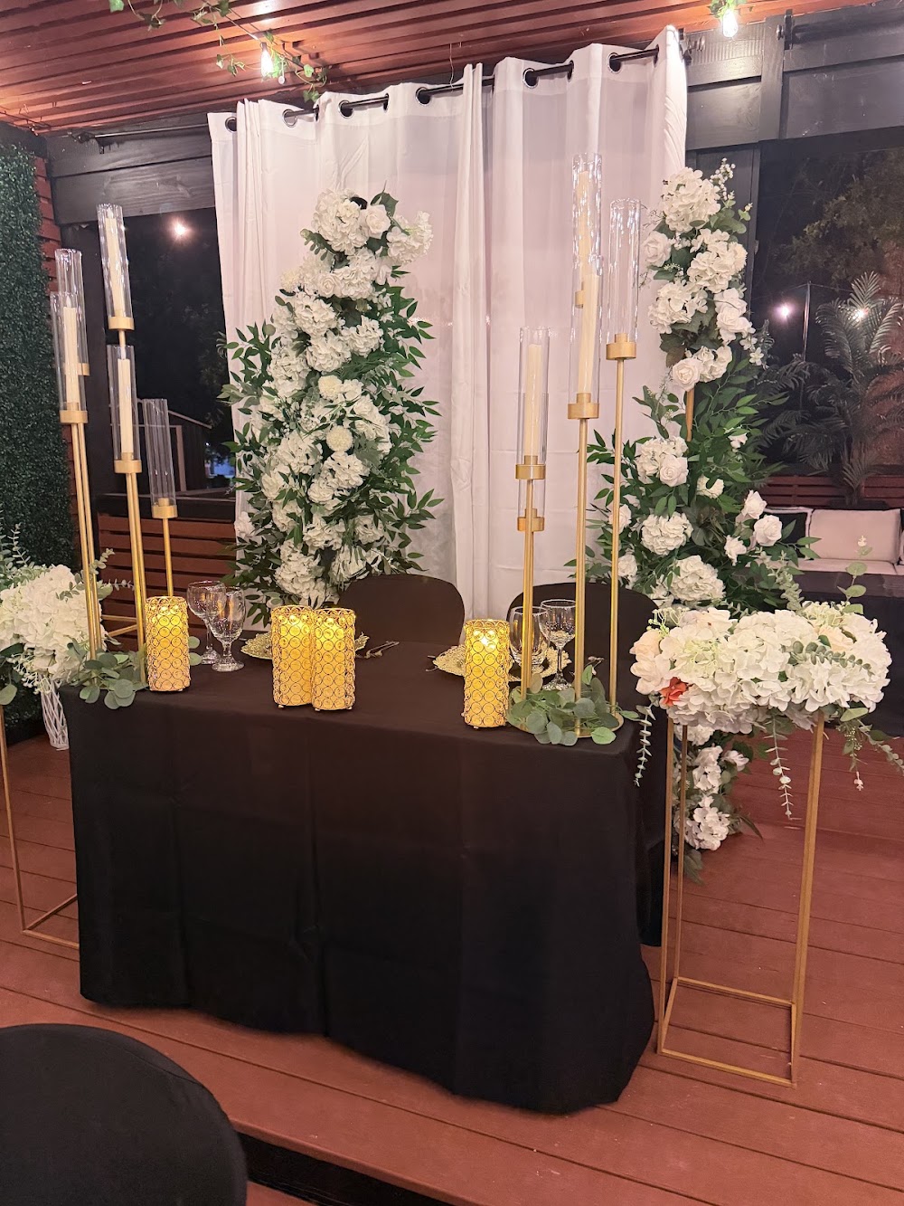 Custom-styled table with white florals, gold candelabras and draped backdrop