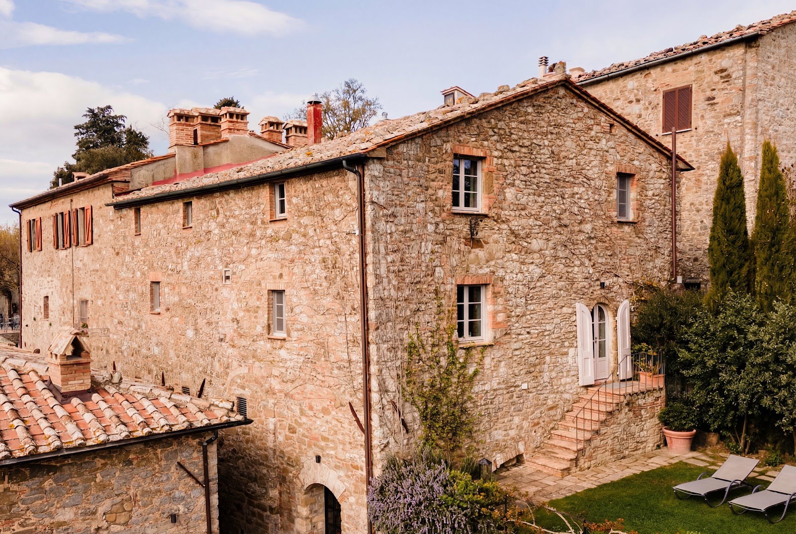 A restored stone house with terracotta roof tiles and shuttered windows in a Tuscan hill village