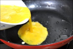 Đun nóng 2 muỗng canh dầu ăn rồi cho trứng vào, dàn mỏng đều mặt trong chảo.