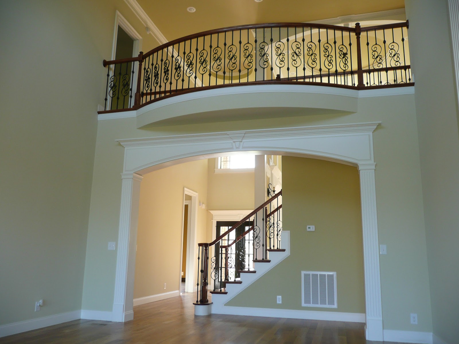 Interior of a West Tennessee residence showing a white decorative archway, a curved balcony with black metal railings, and a staircase with dark wood handrails.