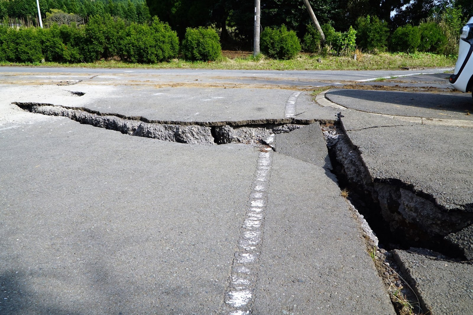 道路陥没のイメージ。ひび割れて段差ができたアスファルトの道路