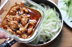 Giờ thì trộn mì với thịt gà, dưa leo, hành lá, mè trắng rang vào chung một cái chảo. Trộn thật đều để sợi mì ngấm đều nước thịt gà cho đậm đà.