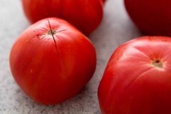 Cà chua rửa sạch, dùng dao khắc chữ X ở phần đáy trái cà chua. Cho cà chua vào nồi nước sôi, chần khoảng 3 phút. Vớt cà chua ra, ngâm trong nước có thêm đá viên, bóc bỏ lớp vỏ.