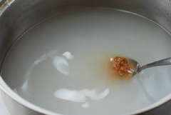 Cho 6 chén nước vo gạo vào nồi, thêm 1.5 muỗng canh tương đậu nành Hàn Quốc, khuấy tan đều, đun sôi. Tiếp đến thêm nghệ, giá đỗ, tỏi băm, đậy nắp, đun sôi khoảng 3-4 phút.