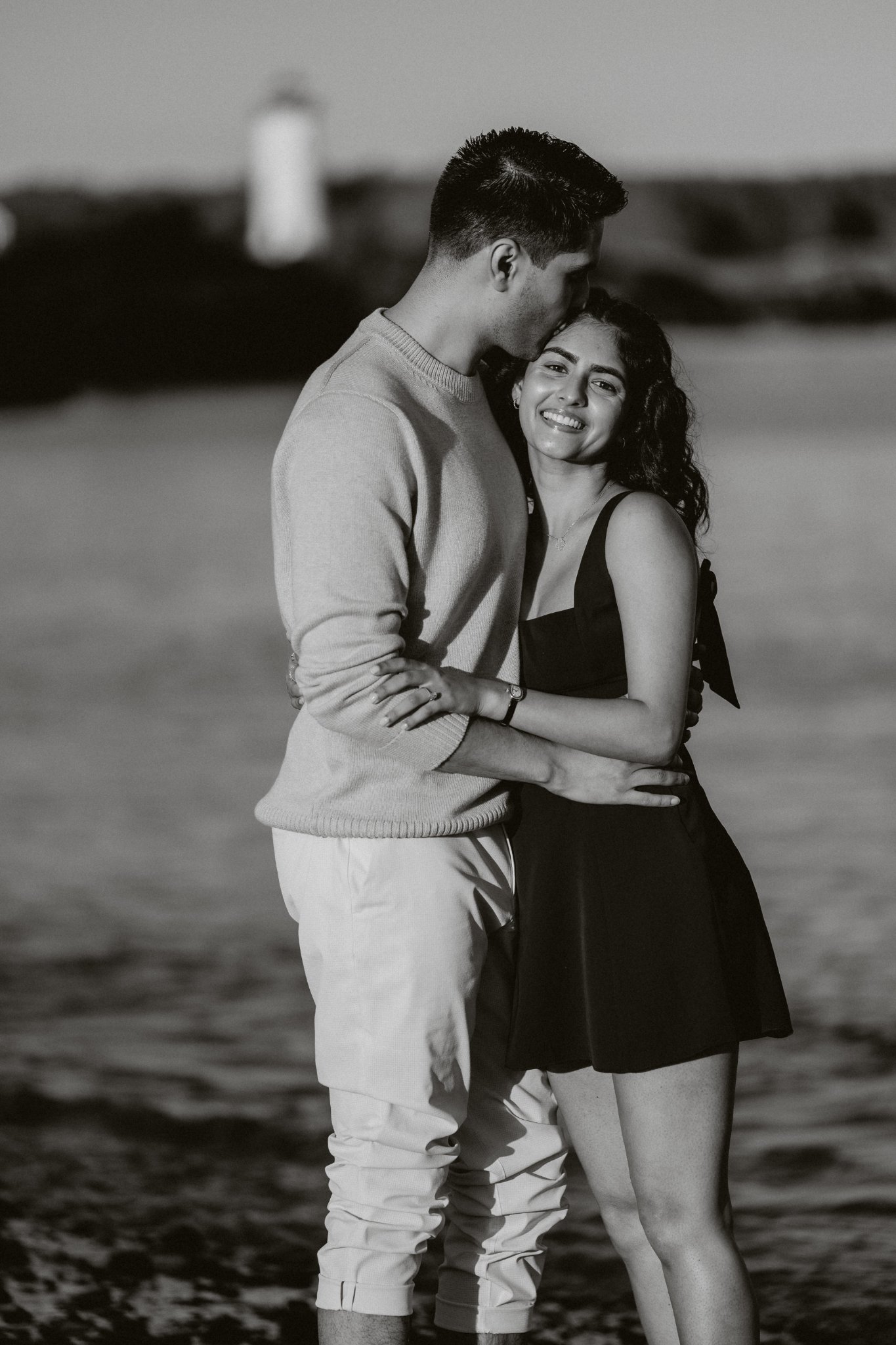 Black and white photo of Sumeet kissing Jasmine's forehead as she smiles