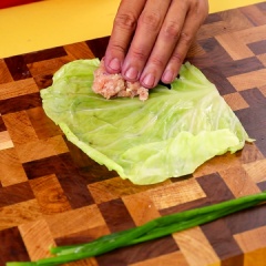 Cho thịt vào bắp cải, cuộn lại, dùng hành lá đã luộc cột lại bằng hành lá đã luộc sơ
