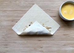 Trải miếng bánh pía lên bàn. Cho phần nhân lên trên bánh pía. Từ từ cuốn tròn bánh pía từ ngoài vào trong ôm chặt phần nhân. Vừa cuốn vừa gấp mép. Nếu khô quá thì bạn có thể dùng trứng gà để chấm bên mép. Làm tương tự cho đến hết nguyên liệu.