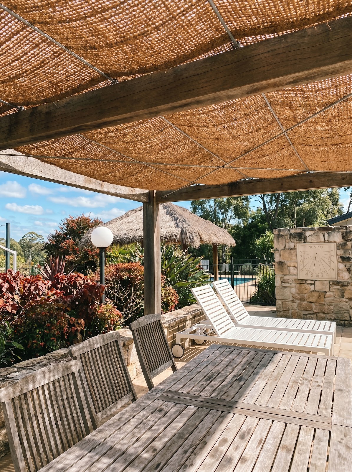 Poolside pergola with woven coir shade canopy and lounge chairs
