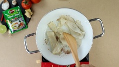 Bắc chảo lên bếp, cho vào 2 muỗng canh dầu ăn, đợi dầu nóng thì cho 15gr hành tím băm vào phi thơm. Tiếp theo cho 150gr măng chua vào xào, nêm thêm 1 muỗng canh đường, 1 muỗng canh ớt sa tế để măng có vị chua ngọt và canh thêm phần cay the cùng màu sắc đẹp hơn. Sau khi xào thì chế vào nồi 700ml nước lọc, đun nước sôi lên thì cho 100gr cà chua cắt múi cau vào nồi.
