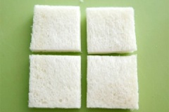 Đầu tiên, cắt bỏ 4 viền ngoài của bánh mì sandwich đi. Sau đó, cắt bánh mì sandwich thành 4 miếng nhỏ.