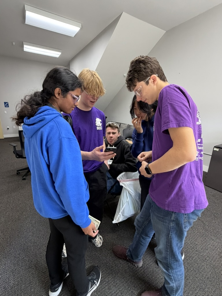 Students checking a phone together in the pits