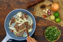 Tiếp theo, cho 50gr hành tây bổ múi cau vào đảo cho hành hơi tái rồi cho thịt bò vào đảo thật nhanh tay.