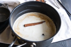 Cho heavy cream, nước và tinh chất vani vào nồi, cho thêm đường nâu cùng thanh quế vào. Bật lửa và đun nồi hỗn hợp, vừa đun vừa khuấy trong khoảng 5 phút cho hỗn hợp hòa quyện với nhau.