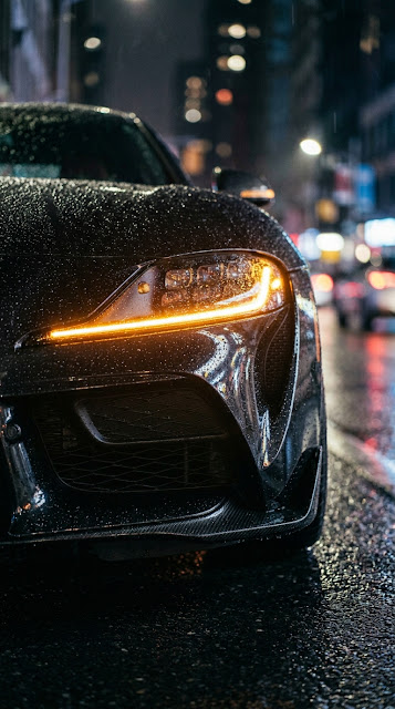 Close-Up of Black Porsche Headlight Covered in Raindrops at Night - Free mobile Wallpaper