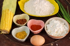 Tách bắp bắp ngọt thành từng hạt rời. Trộn đều bột mì, bột bắp và 1 thìa bột nghệ với nhau. Đổ nước từ từ vào tô bột, khuấy đều tay cho bột tan hết tạo thành hỗn hợp bột sánh. Đập 1 quả trứng vào trộn đều cho trứng tan hòa quyện với bột. Thêm tương ớt, ớt bột và hành lá cắt nhỏ vào tô bột khuấy đều.
