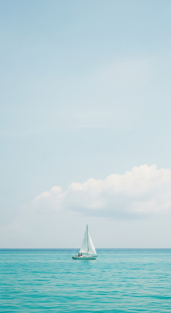 Minimalist Photograph of a White Sailboat on a Calm Turquoise Ocean Under a Soft Sky