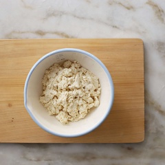 Đậu hũ cho vào tô nghiền nhuyễn. Sau đó thêm vào bột bánh Hot Cake, trộn đều. Rưới từ từ sữa tươi vào để hỗn hợp có độ ướt tương đối. Rải ít bột mì áo ra mặt phẳng để chống dính. Chia khối bột thành những viên nhỏ, vê tròn dẹp.