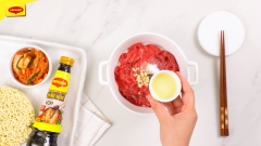 Thịt bò phi lê cắt thành miếng mỏng vừa ăn. Cho thịt bò vào tô, thêm vào 10gr tỏi băm, ½ muỗng cà phê tiêu, 1 muỗng cà phê đường, 1 muỗng cà phê dầu ăn, 1 muỗng cà phê nước tương Maggi, 2 muỗng cà phê dầu hào Maggi rồi trộn đều ướp trong 10 phút.