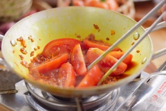 Bắc lên bếp một chiếc chảo sạch, cho vào 3 muỗng canh dầu ăn cùng với 15gr hạt màu điều. Bật bếp và đun nóng dầu đến khi hạt màu điều làm dầu ăn chuyển sang đỏ cam thì vớt ra. Múc ra bớt 1/2 số dầu điều để riêng, cho vào chảo 15gr hành tím băm và 1 quả cà chua cắt múi cau, xào 2 phút cho cà mềm rồi đổ phần cà xào vào nồi nước riêu.