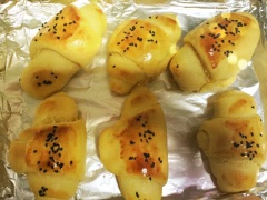 Sau đó chia chỗ bột làm 12 phần đều nhay, vê hình bầu dục, cán dẹp rồi cuộn lại thành hình cua. Xếp bánh ra khay nướng có lót sẵn giấy bạc, phết lên 1 lớp lòng đỏ trứng, rắc ít mè đen, nướng ở 180 độ C trong khoảng 15 phút.