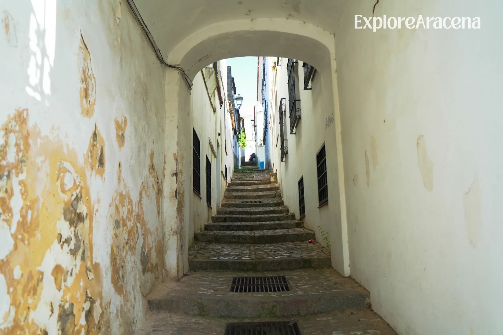 Stone steps climbing through a narrow alleyway between two streets in Aracena.