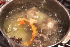 Cho xương bò cùng 1.5 - 2 lít nước vào. Thêm vỏ cam, hoa hồi, gừng thái lát và muối vào, đun sôi. Sau khi nước sôi, bạn vặn nhỏ lửa và hầm cnah trong 1 giờ. Cho đậu phộng vào rồi hầm thêm 2-3 giờ nữa.