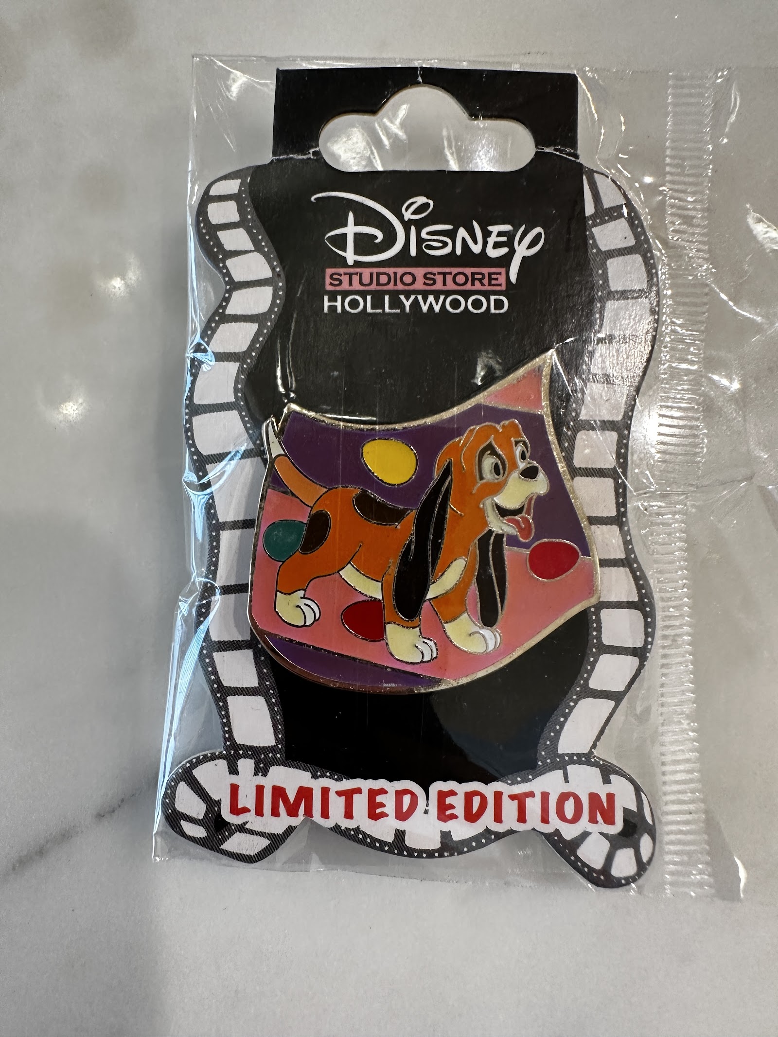 Disney Studio Store Hollywood limited edition hard enamel pin of Copper the hound puppy from The Fox and the Hound, on original black and white film strip backing card