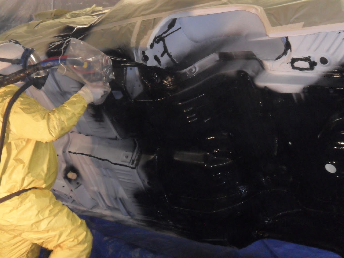 Applicator in protective suit spraying coating inside a vehicle cab