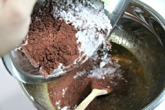 Rây bột mì, baking powder, baking soda, bột cacao vào âu bơ trứng và tiếp tục trộn đều lên cho quyện vào nhau. Đổ bột vào khuôn bánh mì. Bật lò ở 170 độ C, cho bánh vào nướng 45 - 55 phút, dùng tăm kiểm tra thấy bánh khô là đã chín.