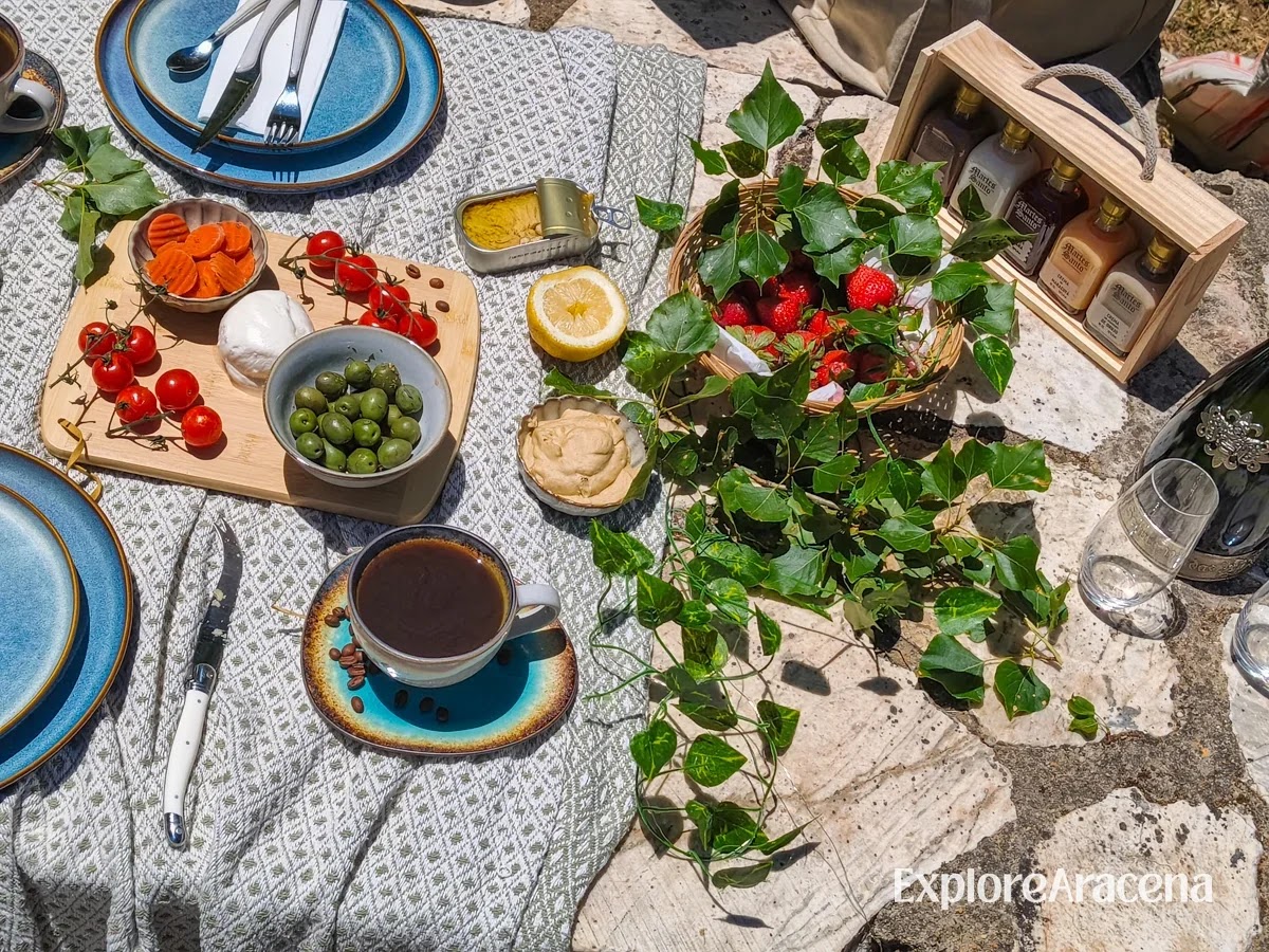Local food and a bottles of Martes Santo liqueur arranged for a picnic on a stone table at Marimateos.